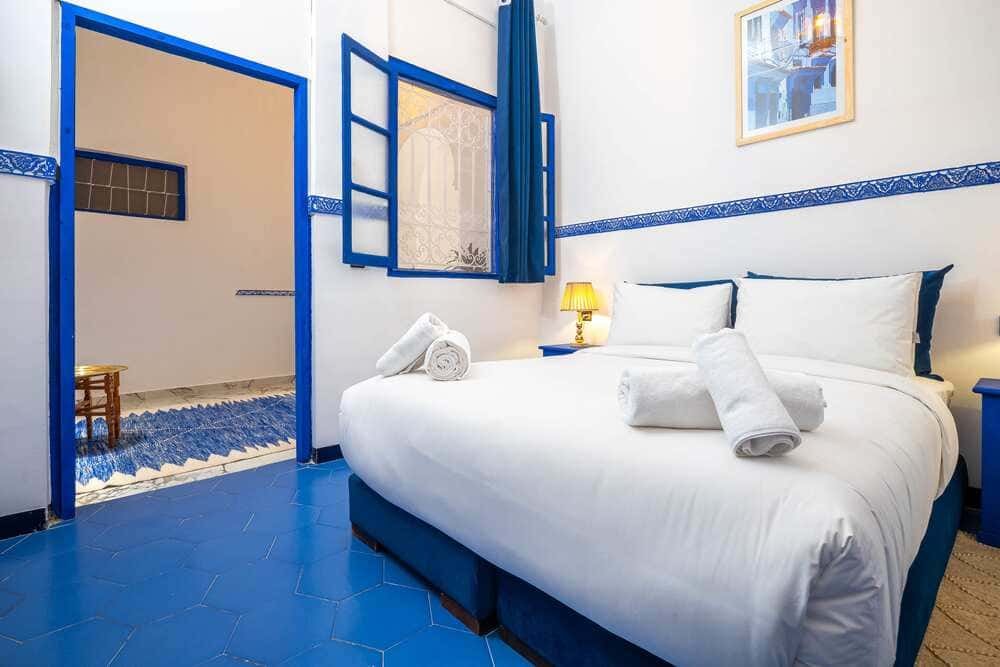 Habitación de riad en Marrakech, con cama, ventana con celosía y baño privado.