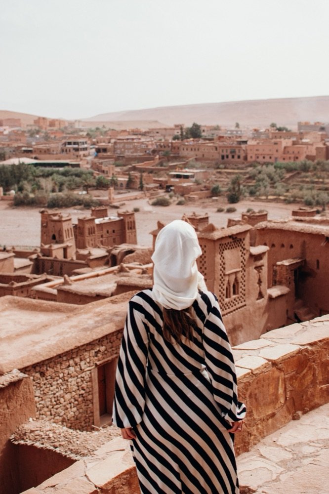 Una viajera de espaldas en una azotea de Aït Ben Haddou, mirando el valle.